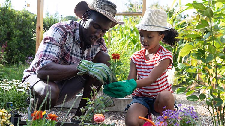 Padre e hija celebran el Día de la Tierra plantando flores.