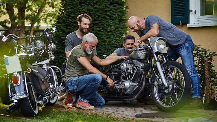 Cuatro amigos con motocicletas frente a una casa