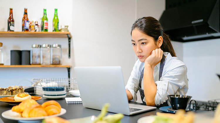 Una mujer sentada frente a una computadora piensa en su negocio.