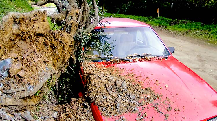Carro rojo cubierto con escombros de un deslizamiento de tierra.