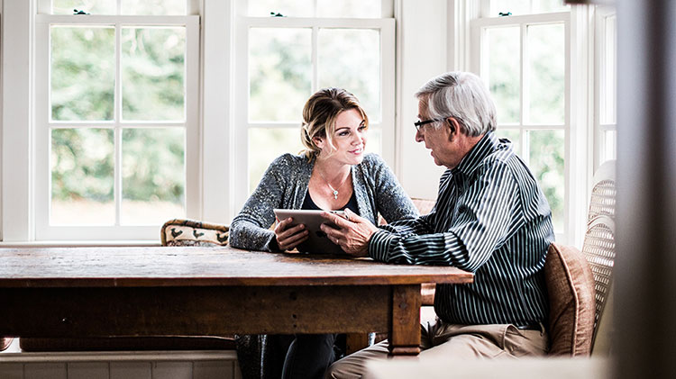 Una mujer utilizando una tableta con su padre.