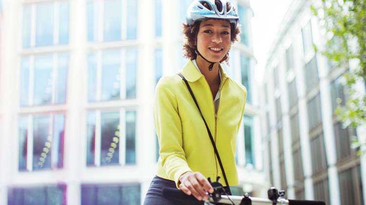 Una mujer con casco se dirige al trabajo en bicicleta.