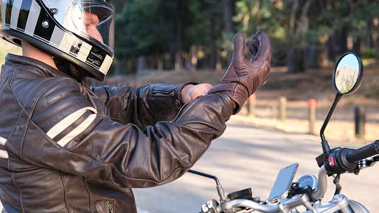 Un motociclista se pone un guante de motocicleta.