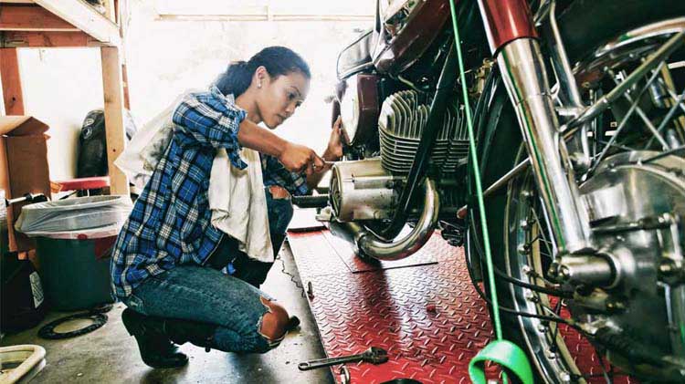 Una mujer trabajando en una motocicleta en un garaje