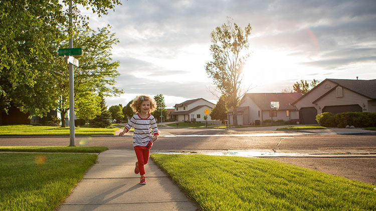 Una niña corriendo en un vecindario sin peligro gracias a las redes sociales de vecindarios.