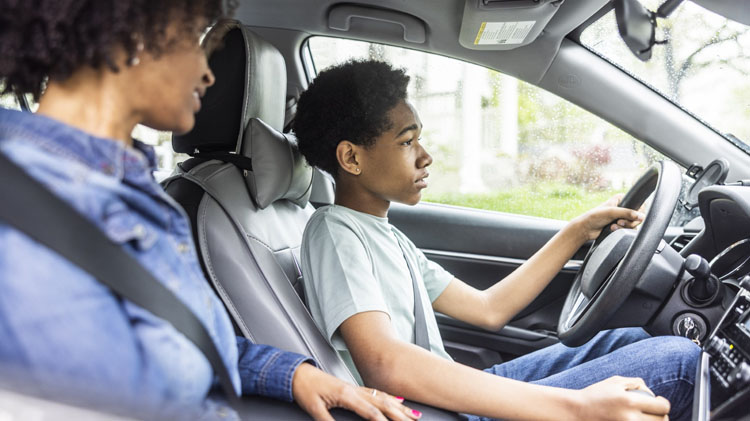 Una madre enseñando a su hijo a manejar un carro.