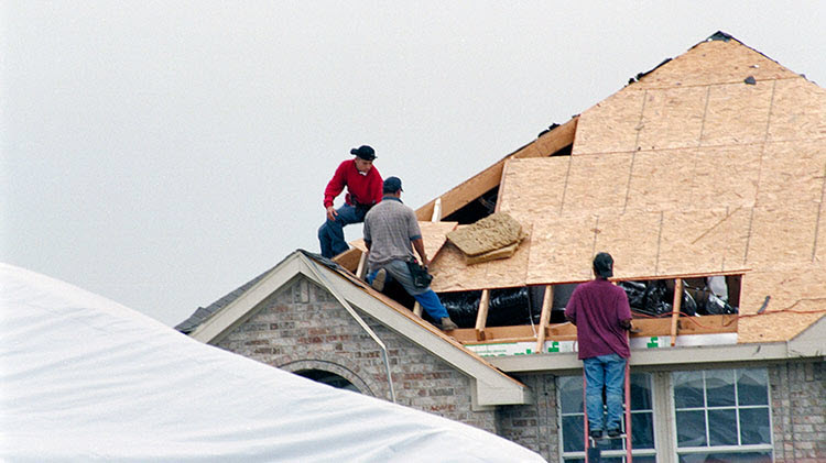 Contratistas arreglando un tejado tras una tormenta.