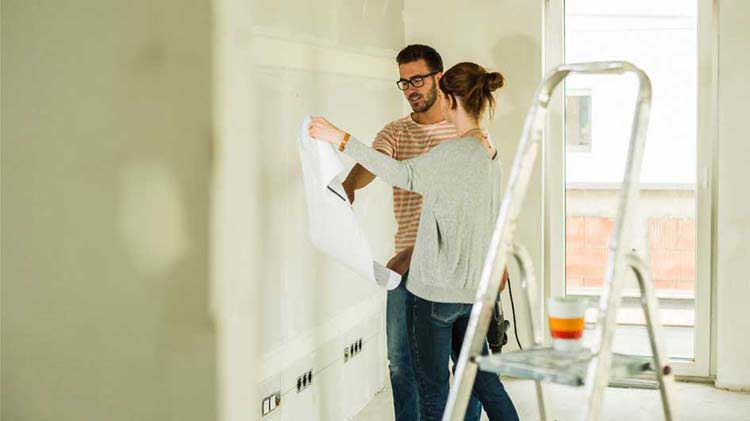 Una pareja pintando la sala de su vivienda