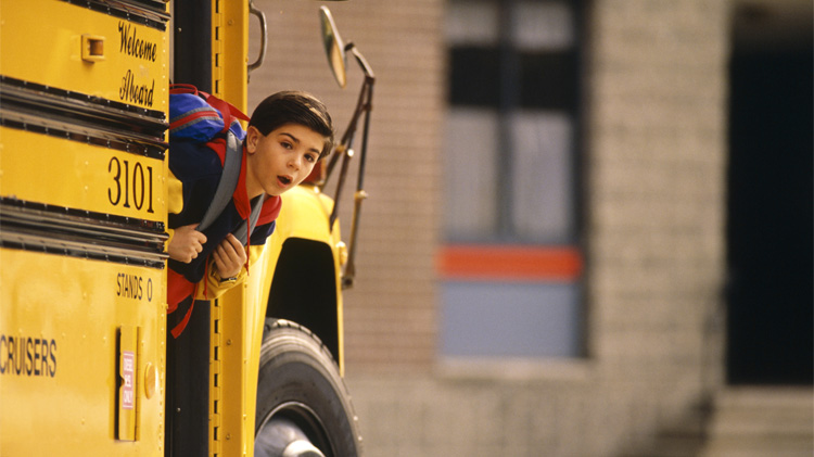 Niño practicando seguridad del autobús escolar, mirando sus alrededores antes de bajarse del autobús escolar