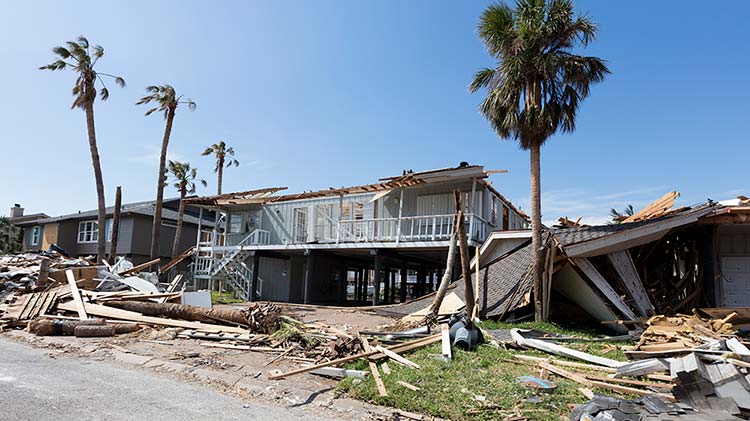Daños a una casa y a edificios circundantes causados por una tormenta de viento.