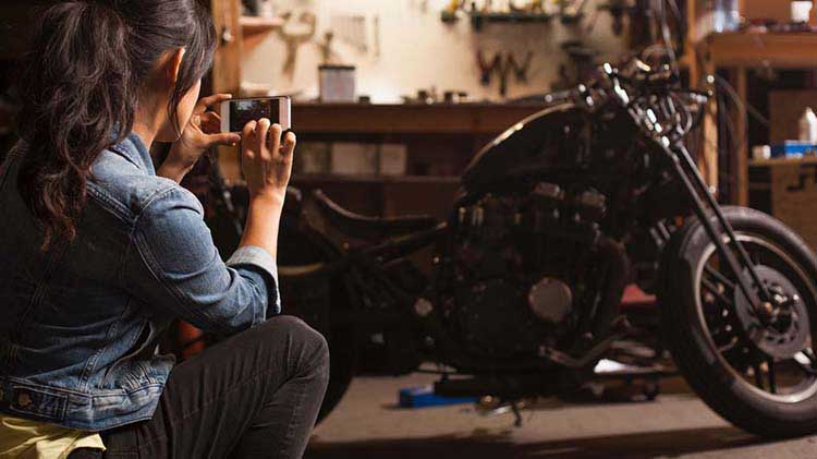 Mujer tomando una foto de su motocicleta con su teléfono.