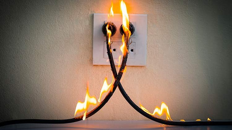 Cables eléctricos enchufados a una pared están en llamas debido a un arco eléctrico.