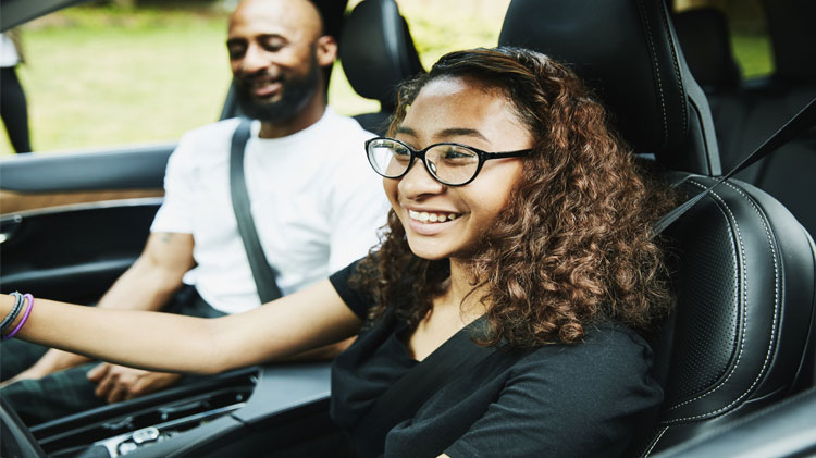 Conductora adolescente sonriendo dentro del carro con su papá