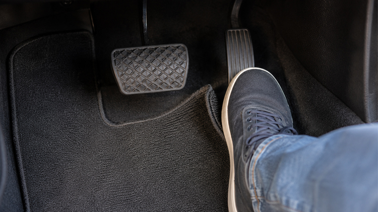Pie sobre el pedal de un vehículo.