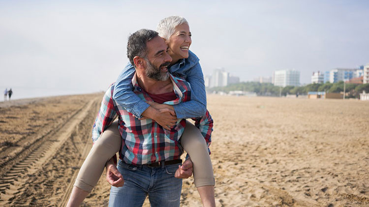 Una pareja en la playa disfrutando de los resultados de su planificación de ingresos por jubilación.