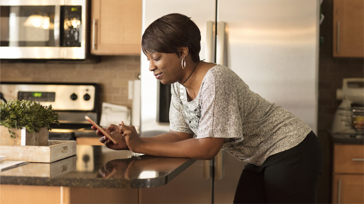 Una mujer usando el teléfono celular inteligente para escoger comunicaciones digitales.