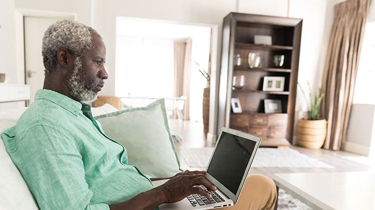 Hombre usa su computador portátil para trabajar en su testamento y planificación de patrimonio.