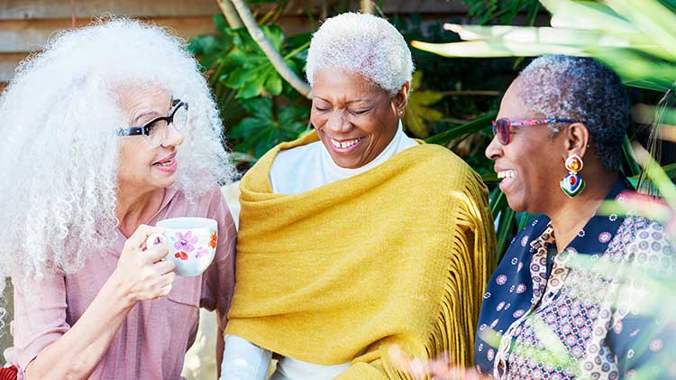 Tres mujeres riendo mientras discutían su jubilación y se sentaban a un lado tomando café.