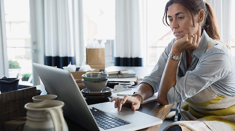 Mujer en su escritorio con una laptop abierta mientras trabaja desde casa.