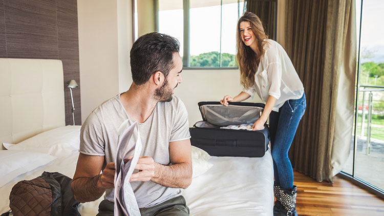 Una pareja desempaca para disfrutar de su estadía en un hotel.