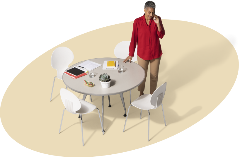 Una mujer habla por teléfono estando de pie junto a una mesa